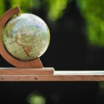 Petit globe terrestre en bois, support incurvé, sur planche, fond vert flou